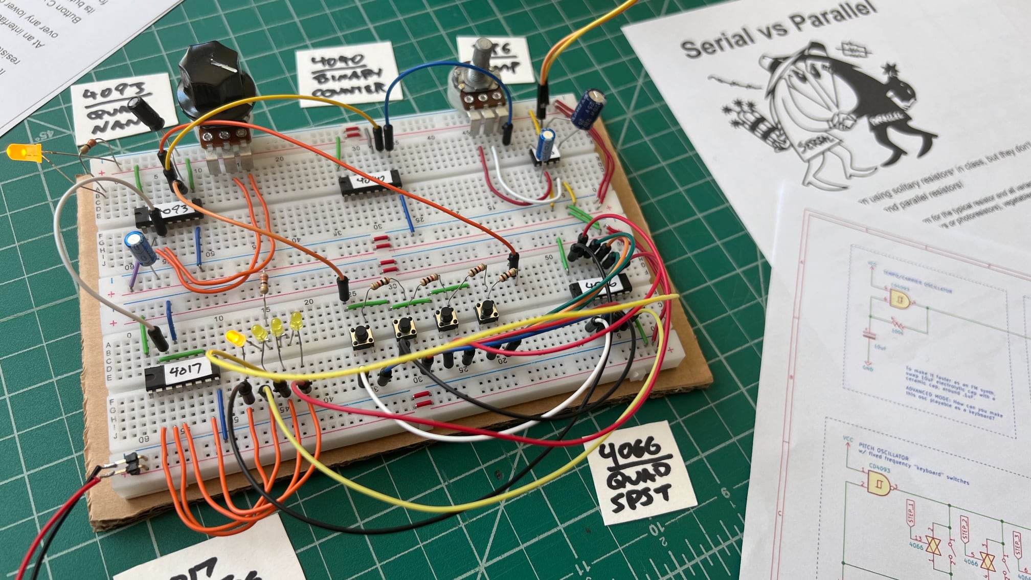 Photo of keyboard sequencer on breadboard with printed schematic and accompanying "Serial vs Parallel" doc